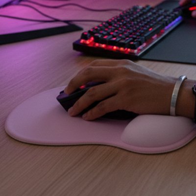 Main posée sur une souris et un tapis ergonomique rose pour prévenir le syndrome du canal carpien.