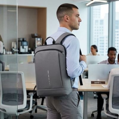 Sac à dos ordinateur portable gris foncé ergonomique porté par un homme actif dans un espace de travail.